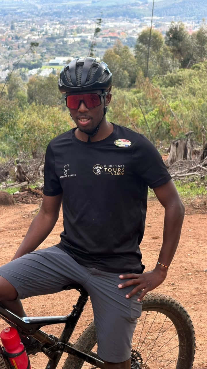 Kusaselihle Ngidi seated on his mountain bike above the Stellenbosch vineyards